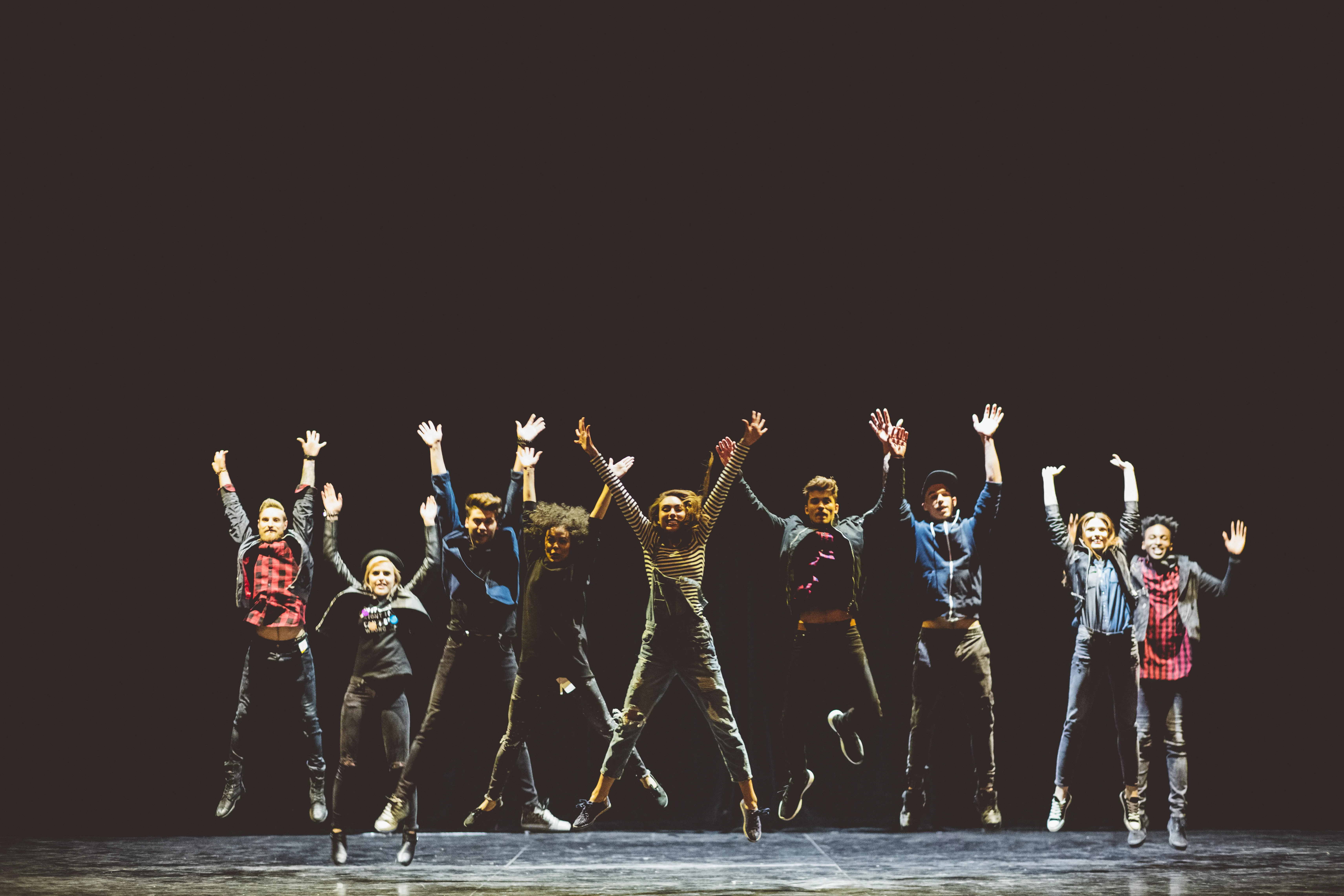 Des eleves d'une classe de theatre sautant tous ensemble sur une scene, chez Act In Mad represente l'esprit d'equipe